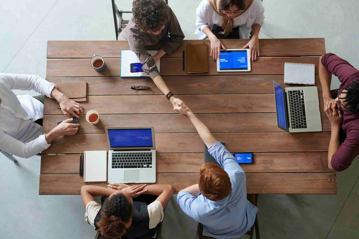 Birds eye view of employees around a table with laptops having a meeting