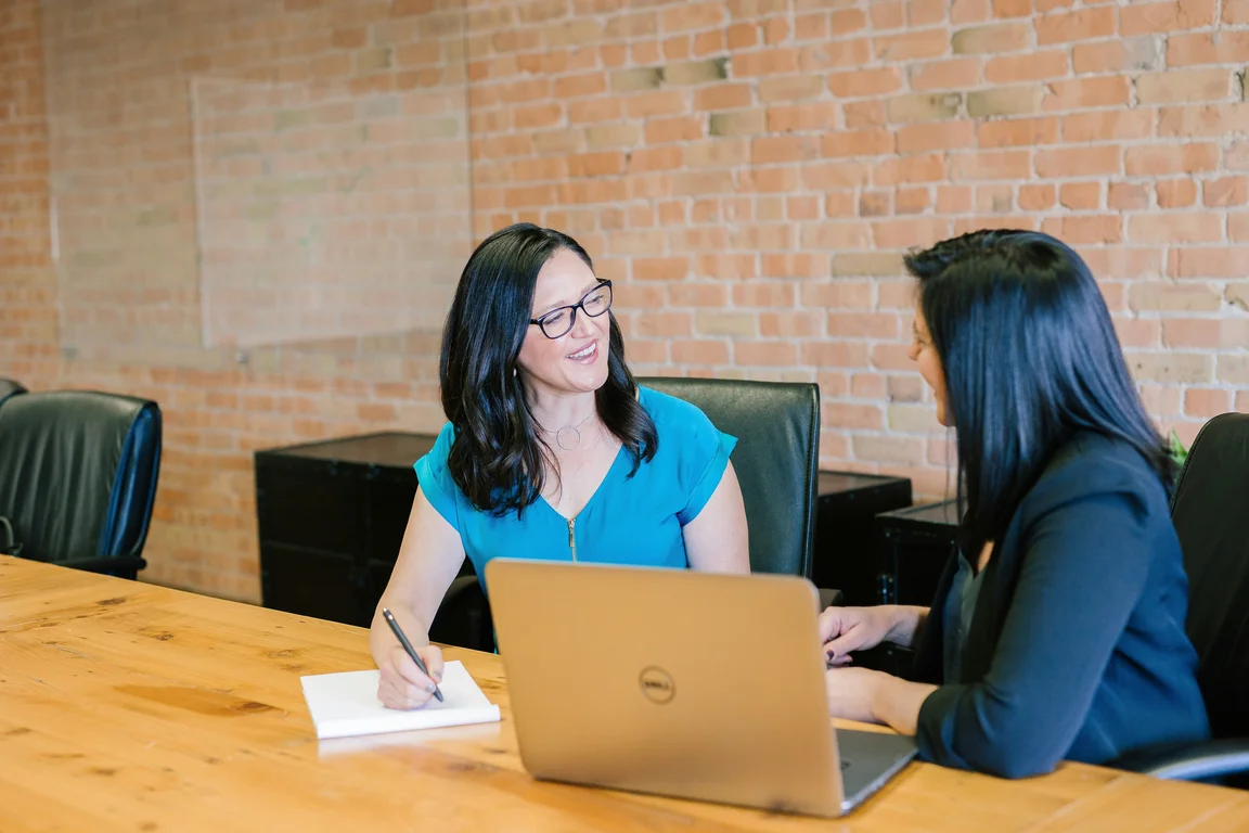 Women having a conversation with laptop and notepad