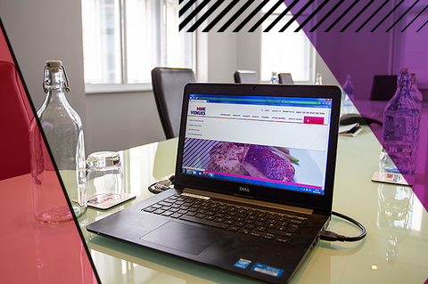 Laptop on a table next to a bottle of water and upturned glass. Laptop displays the MakeVenues website.