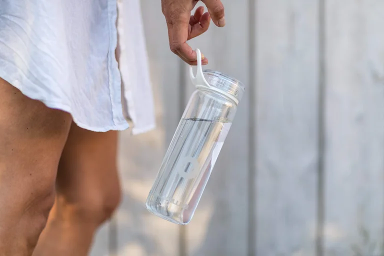 Person holding a reusable plastic water bottle 