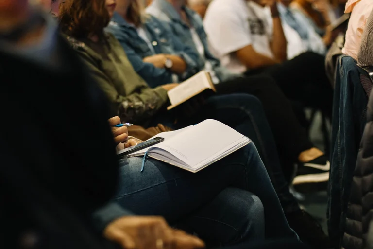 People sat at a conference with notebooks