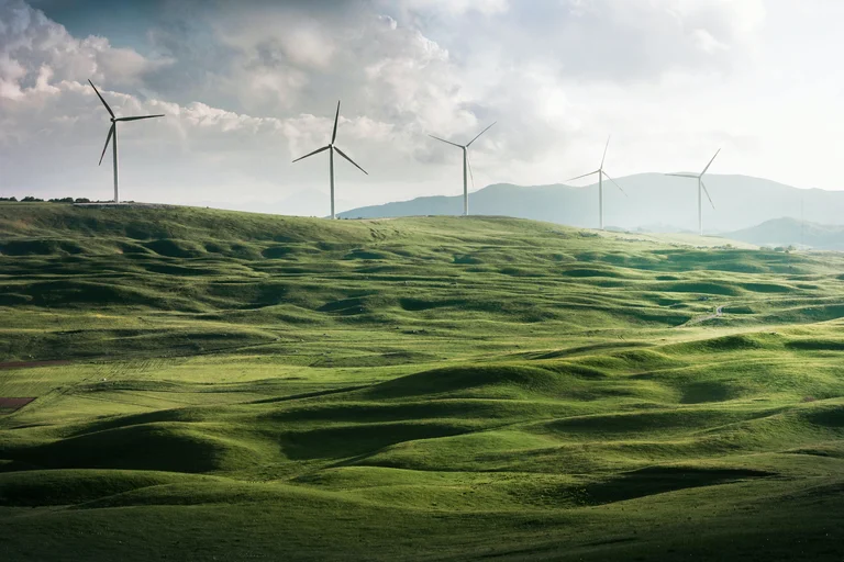 Rolling hills with five wind turbines sitting in the distance.